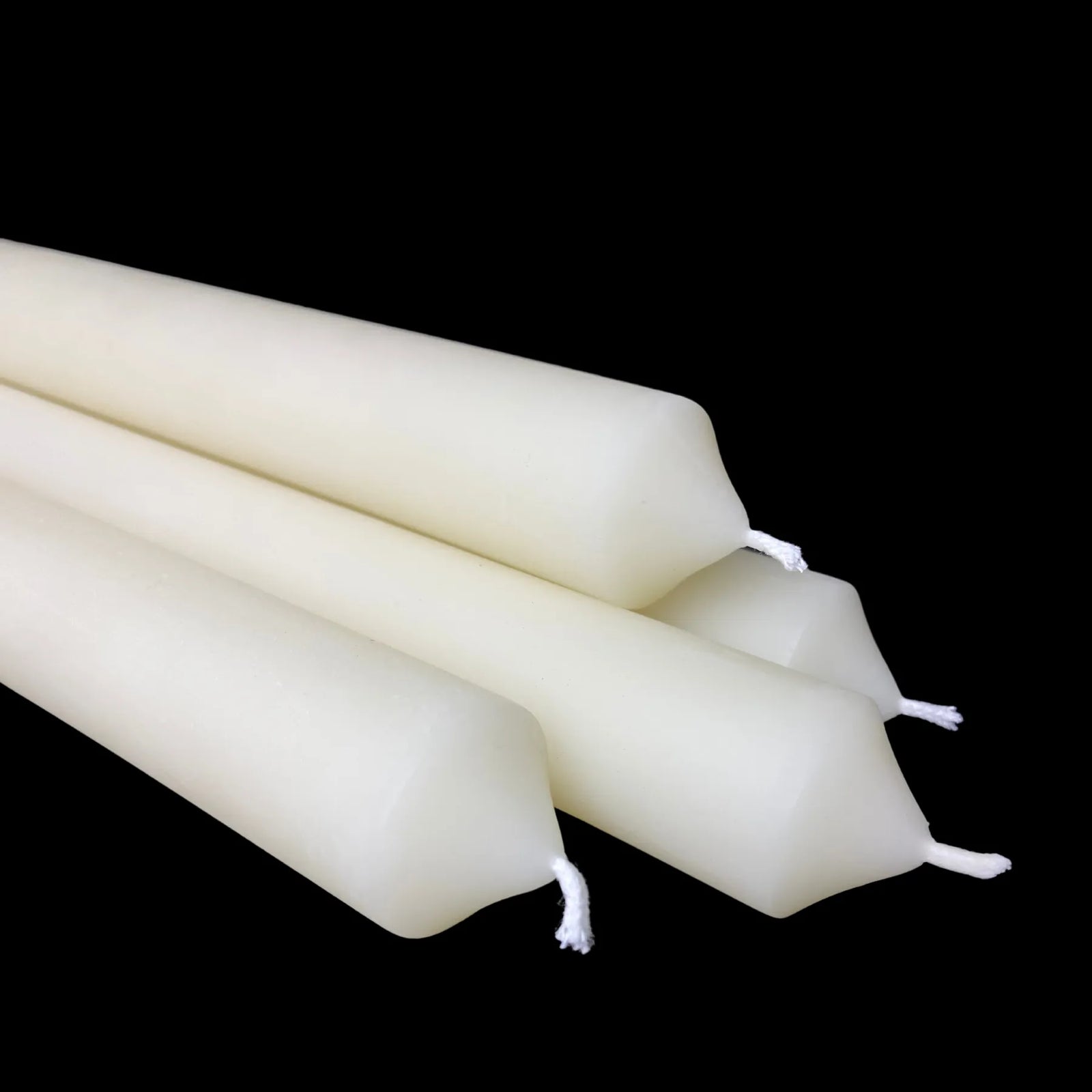 Close-up of white beeswax tapers showing cotton wicks and smooth wax, 1-inch diameter