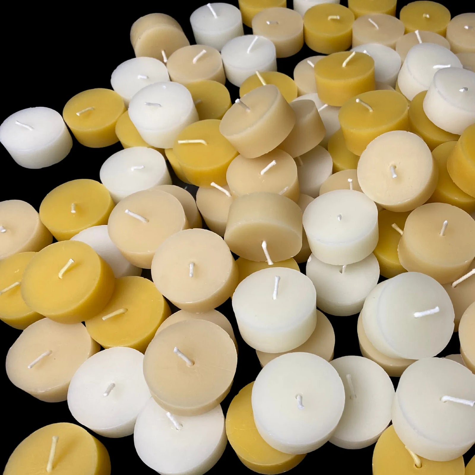 Close-up of mixed beeswax tea lights with cotton wicks, white, yellow and ivory