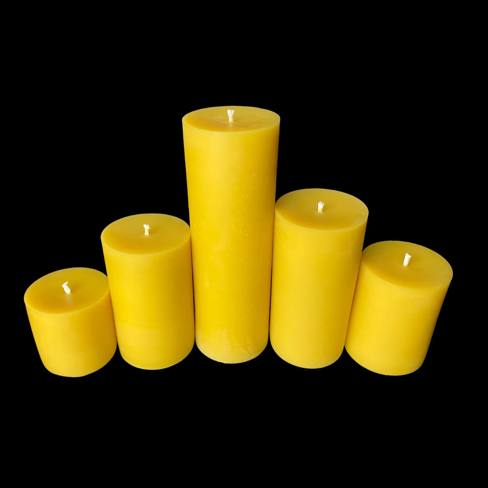 Five-piece yellow beeswax pillar set in graduated heights for festive dining or cozy interiors.