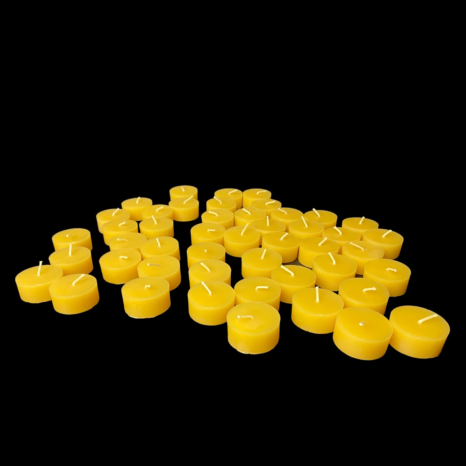 Small bunch of yellow beeswax tea lights on black, 100% beeswax