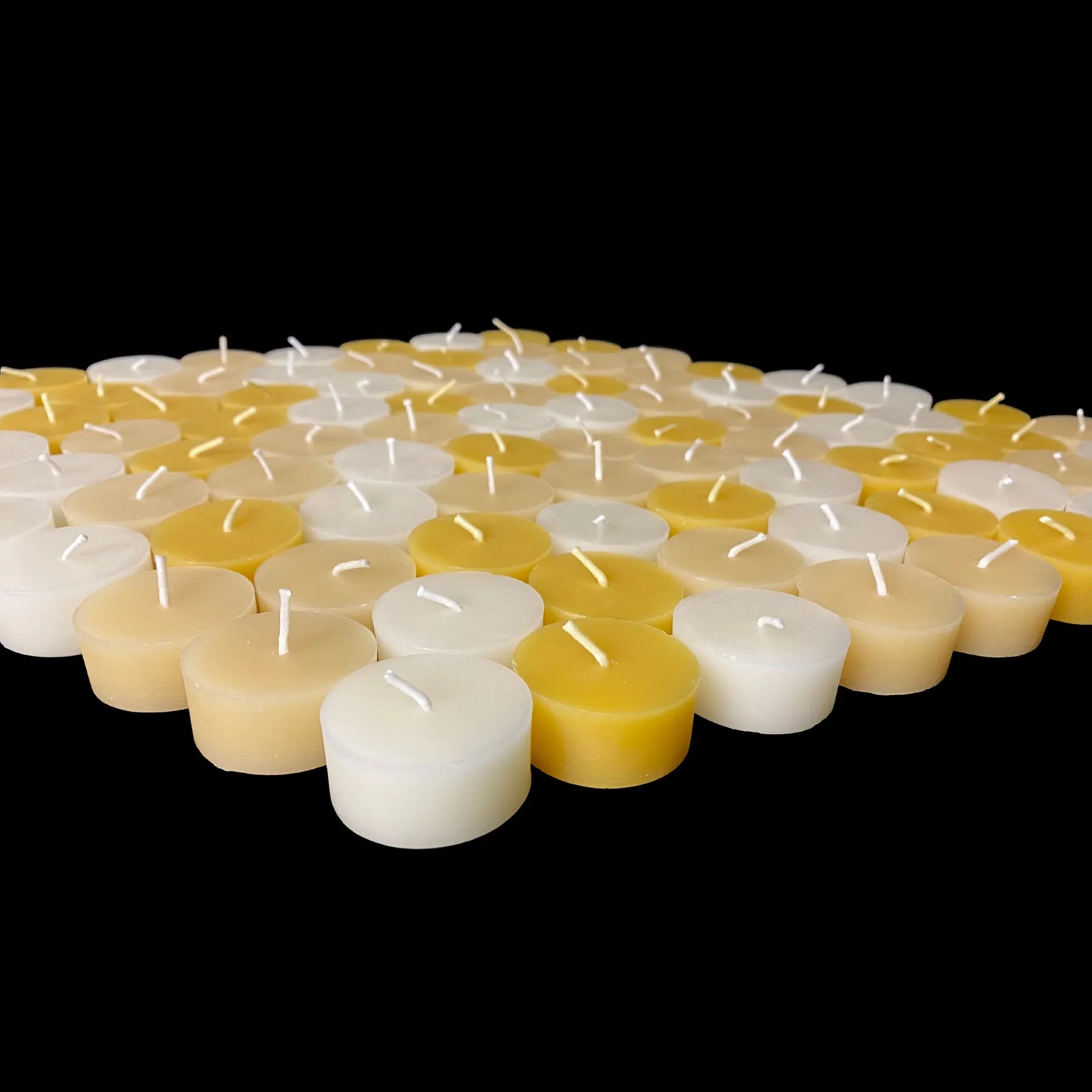 Wide bulk spread of natural beeswax tea lights in white and ivory, 1.43 in