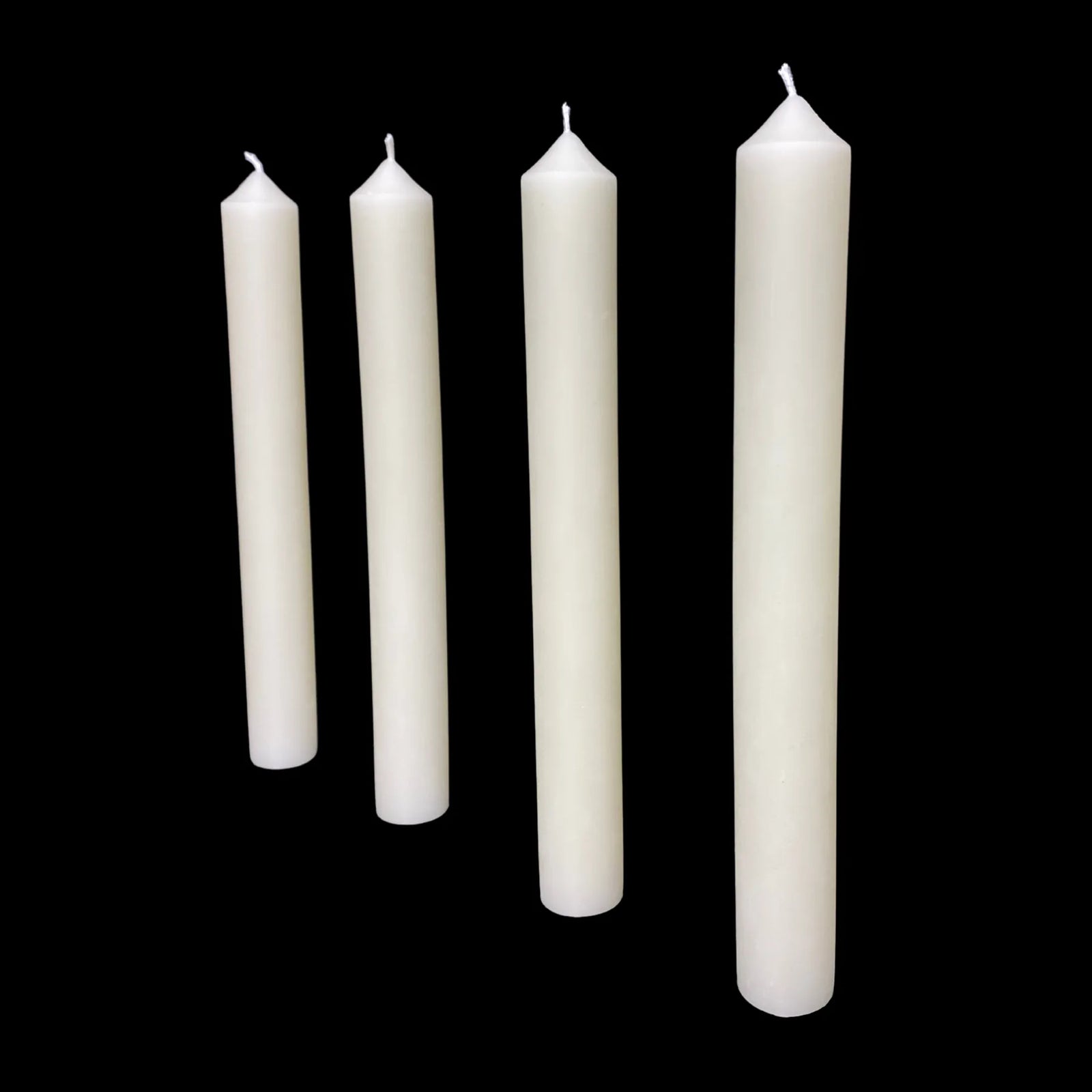 Four white dripless beeswax taper candles standing in a row, each 1" thick