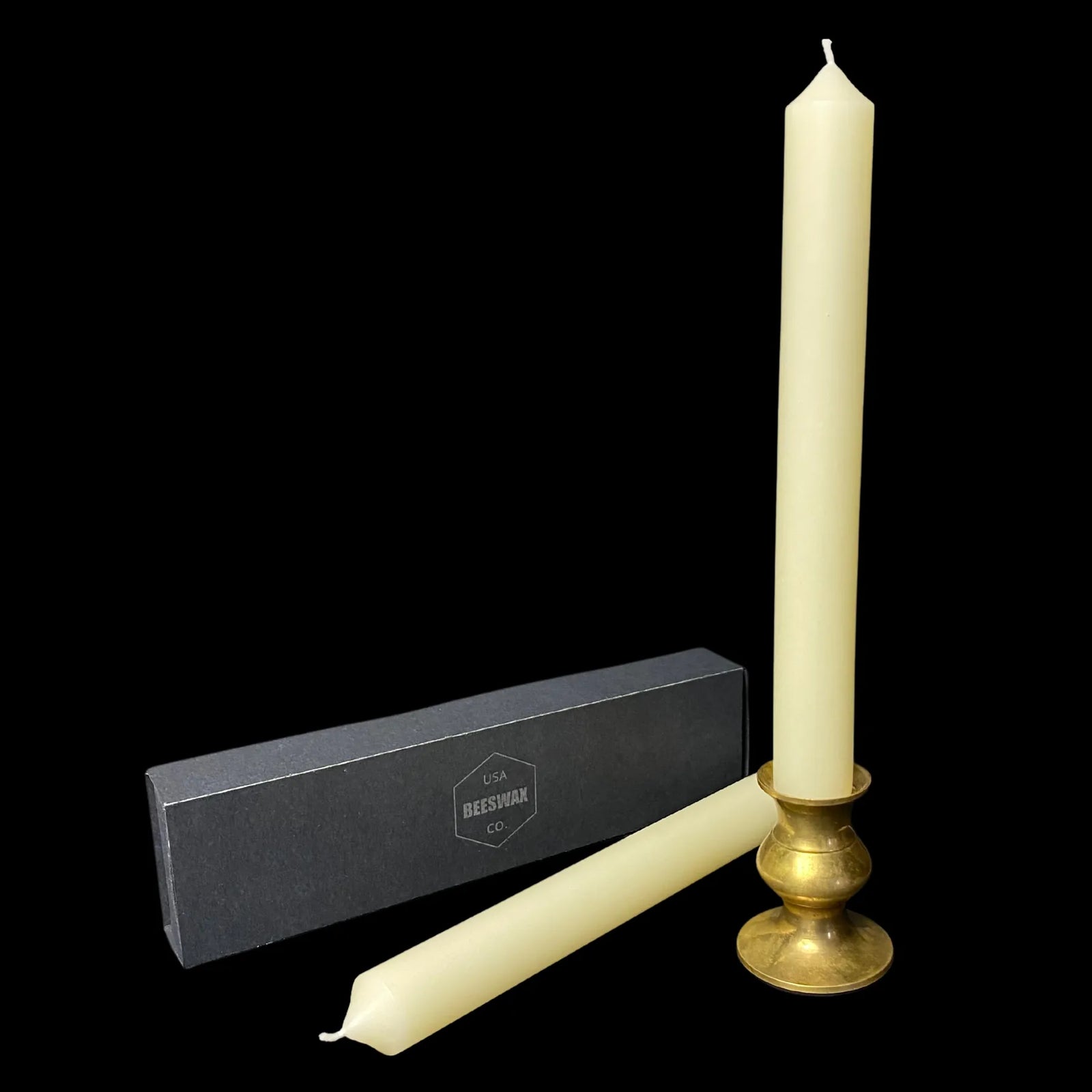 White beeswax taper candle in a brass candlestick holder for a dinner table, 1 inch thick