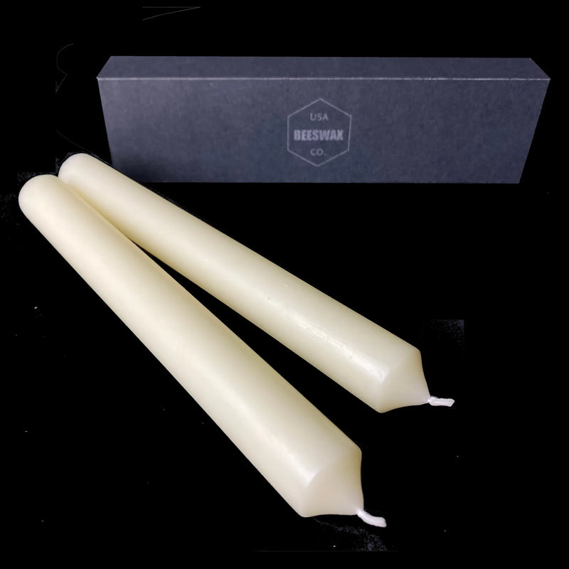 White beeswax dinner tapers lying in front of a branded gift box, 1" diameter