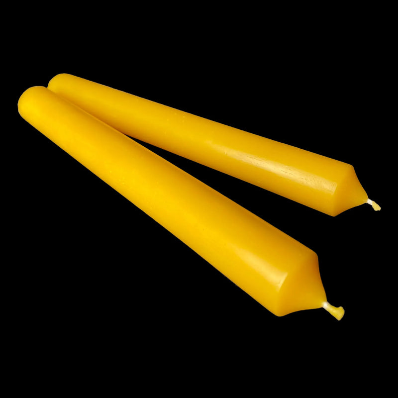 A pair of yellow beeswax dinner tapers on black, 1" diameter, with a honey scent