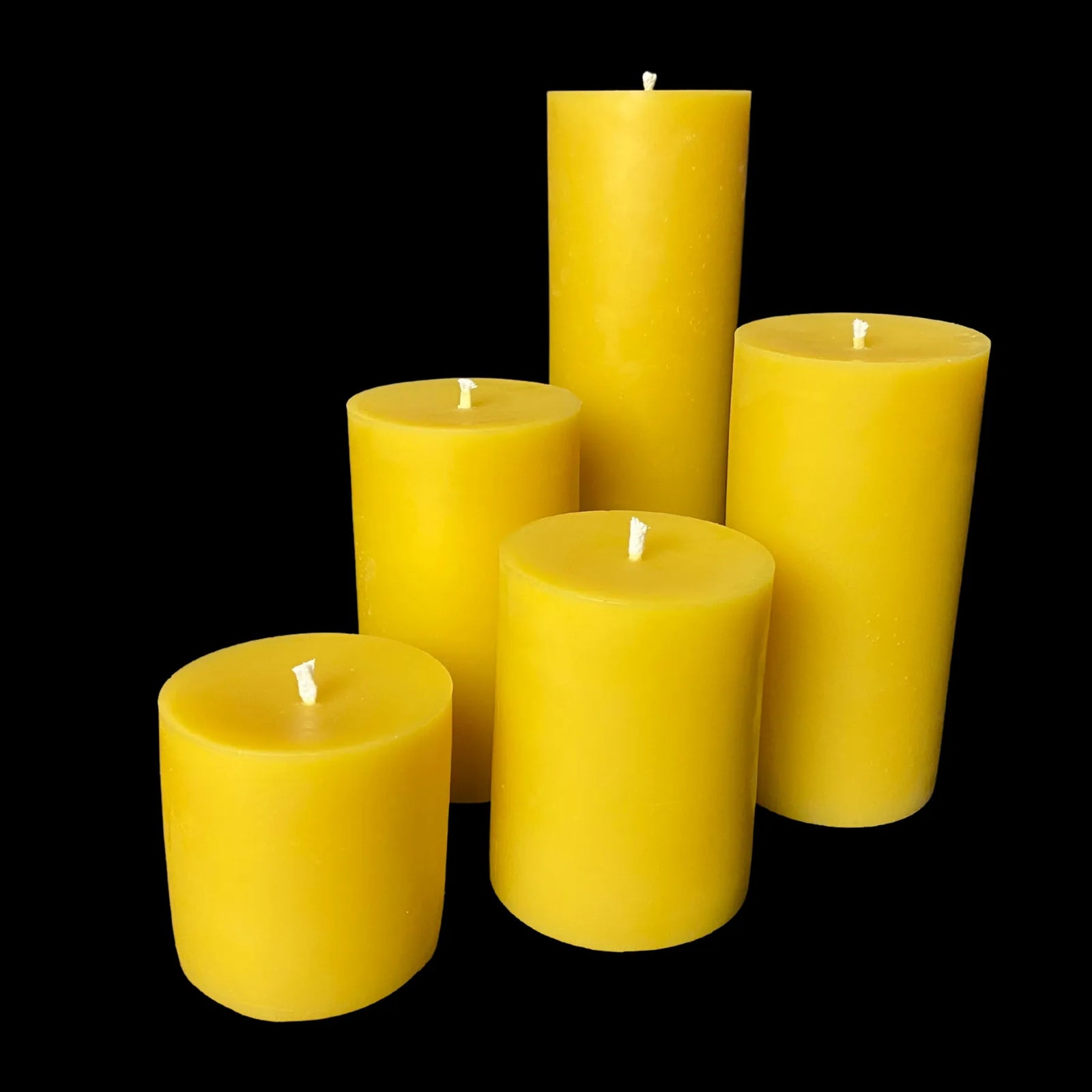 Set of five handcrafted 3-inch yellow beeswax pillar candles in assorted heights.